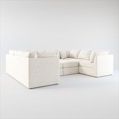 a white sectional couch with pillows on it's back and side facing the camera