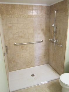 a white toilet sitting next to a shower in a bathroom with beige tile on the walls