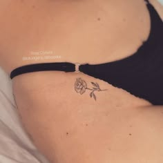 a woman's stomach with a rose tattoo on her left side ribcage