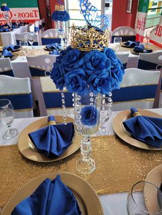 the table is set with blue flowers and gold place settings for an elegant dinner party