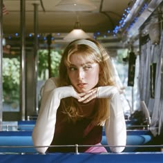 a woman sitting on a bus with her hand resting on the seat and looking at the camera