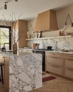 a kitchen with marble counter tops and wooden cabinets, along with an island in the middle