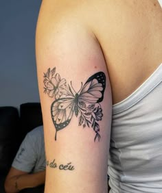 a woman's arm with a butterfly and flowers tattoo on the left side of her arm