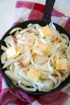 a skillet filled with pasta and cheese on top of a red and white checkered towel