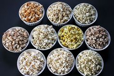 six cups filled with different types of popcorn on top of a black tablecloth covered surface