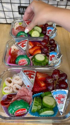 two plastic trays filled with fruit and veggies on top of a wooden table