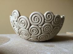 a white bowl sitting on top of a table next to a cup with spiral designs