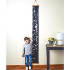 a little boy standing next to a tall ruler