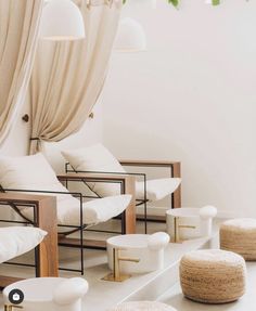 a room with white chairs and plants hanging from the ceiling in front of them,