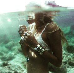 a woman standing under water holding a cell phone