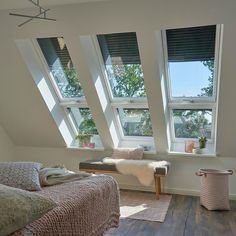 a bedroom with three large windows and wooden floors