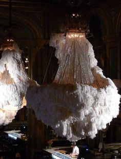 two chandeliers hanging from the ceiling in a room with many lights on them