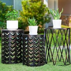 three metal planters with plants in them sitting on the grass next to each other