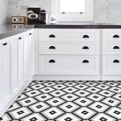 a bathroom with black and white tiles on the floor, counter top and sink area