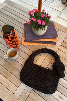 a crocheted purse sitting on top of a wooden table next to a cup of tea