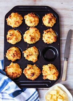 muffins with cheese and butter on a baking tray next to a bowl of butter