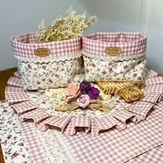 two baskets are sitting on top of a table with flowers and other things in them