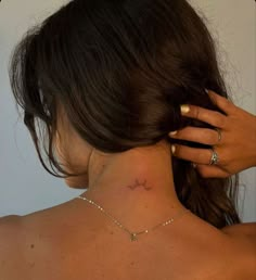 the back of a woman's neck with a small star tattoo on her left side