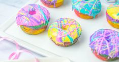 colorful donuts with icing and sprinkles are on a white tray