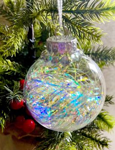 a glass ornament hanging from a christmas tree with colorful glitters on it