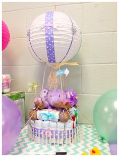 there is a cake with teddy bears in the center and balloons on the wall behind it