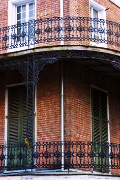 a clock on the side of a building with iron railings and balconies