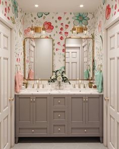 a bathroom with two sinks, mirrors and flowers on the wall