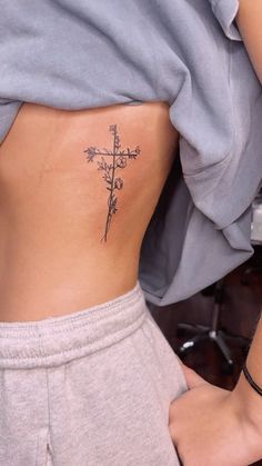 a woman with a cross tattoo on her lower back, showing it's side