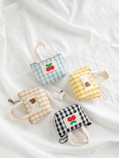 three small purses sitting on top of a white bed next to an apple patch