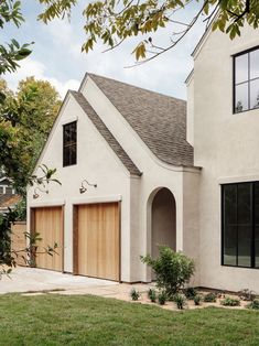 a white house with two garages on the front and one in the back yard