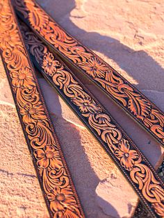 two brown leather leashes sitting on top of a stone floor next to each other