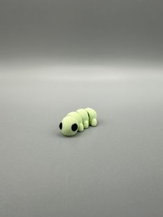 a green caterpillar sitting on top of a gray surface