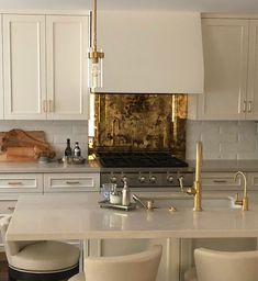 a kitchen with white cabinets and gold accents