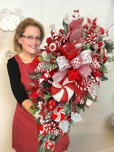 a woman is holding a christmas wreath with candy canes and candies on it