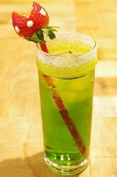 a green drink with a strawberry on the top and strawberries sticking out of it