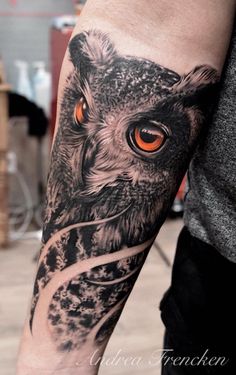 an owl with orange eyes is on the arm