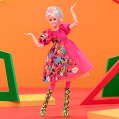 the doll is wearing a colorful dress and high heeled boots with her arms in the air