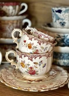 an assortment of teacups and saucers on a wooden table with other dishes