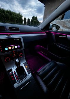 the interior of a modern car with purple lighting and dashboard controls, along with an entertainment center