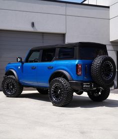 a large blue truck parked in front of a garage with two tires on it's sides