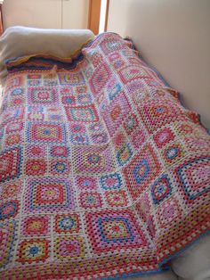 a crocheted blanket is laying on a bed