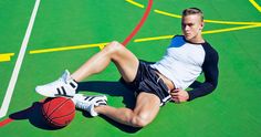 a man laying on the ground with a basketball in his hand and wearing white sneakers