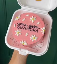 someone holding up a pink cake in a plastic container with writing on it that says, mama journ seniora