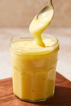 a spoon full of mayonnaise sitting on top of a wooden cutting board