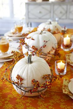 the table is set with white pumpkins and candles