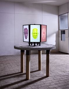 a table with three pictures on it in front of a wall and flooring area