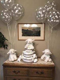 a table with balloons and stuffed animals sitting on it's top tier, in front of a painting