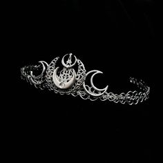 Selene Tiara Part of our New Moon range, this beautiful tiara is adorned with silver moons and tiny silver rhinestones. Perfect to add a witchy vibe to your outfit. The outer rim is lined with heart shaped filigree.  Why not check out our chokers and earrings to make a matching set! Handmade to order, ready in 1-2 weeks. ------------------------------------------------- Headwear Guide -Headwear comes in one size which is flexible . -Do not submerge in water or in intense heat as this may cause wear damage to the item. -Customisations can be requested before purchase such as other colours, different adornments, gem colours etc. The level of change may result in additional costs. -As these items are handmade, small variations may occur. We try to replicate each item as accurately as possible Witch Headpiece, Luna Goddess, Alternative Accessories, Gothic Crown, Gothic Engagement Ring, Goddess Crown, Triple Moon Goddess, Beautiful Tiaras, Wiccan Jewelry