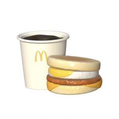 a mcdonald's breakfast sandwich next to a cup of coffee on a white background