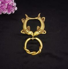 two gold rings with fish on them are sitting next to some flowers and purple flowers